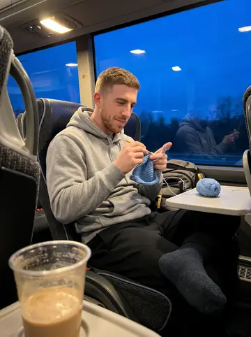 Landon, AI character: back row of the team bus on a road trip, phone propped on the small tray table beside a half-empty coffee