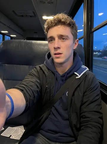 Ronald, AI character: team bus rolling through Pennsylvania at dusk, vinyl seat and dark highway window behind him
