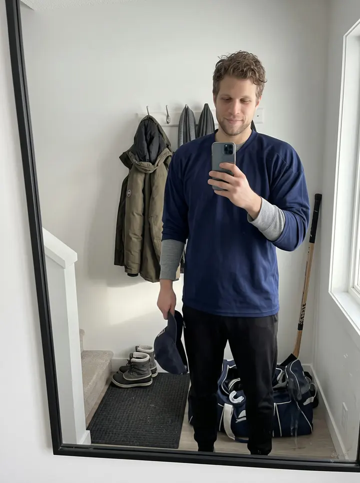 Blaine, AI character: the empty minor-league arena in Thunder Bay after morning skate, standing near the boards with the fresh…