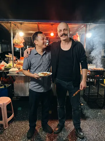 Bogdan, AI character: a neighborhood bar in Ukrainian Village with a padded arm wrestling table, neon beer signs and a crowd of…