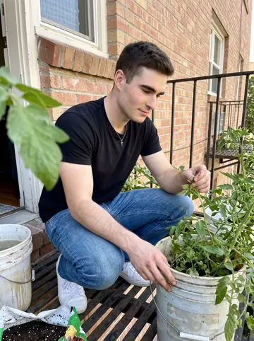 Matvey, AI character: the narrow fire escape outside his Sacramento apartment with tomato buckets lined against the rail