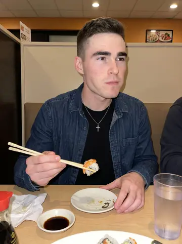 Matvey, AI character: a cheap Tuesday sushi place in Sacramento after late training, sitting in a booth with friends just…