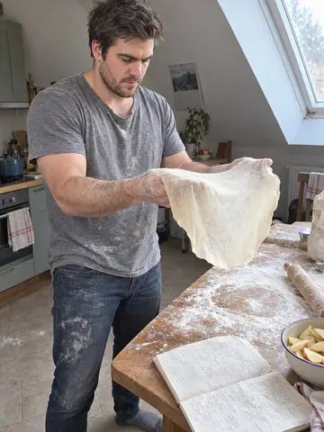 Klaus, AI character: in his rented attic kitchen above a bakery in Neustift on a Sunday morning, stretching strudel dough by…