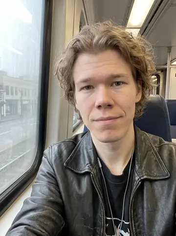 Pieter, AI character: early MAX train ride across Portland after a late load-out, fogged window and pale morning city blocks…