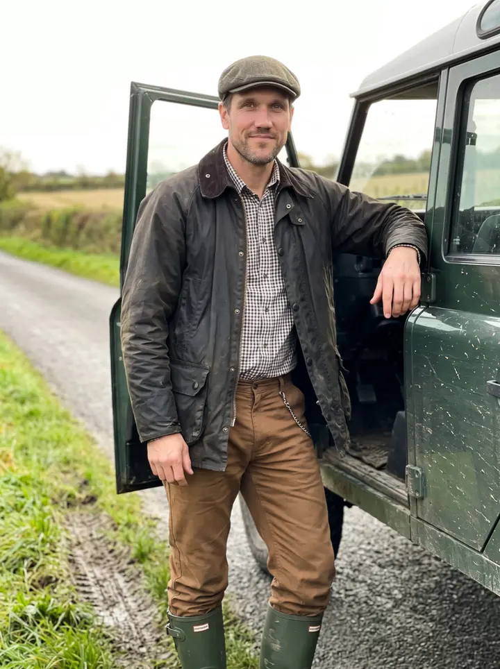 Ruairi, AI character: a narrow border road outside Dundalk, standing beside the open door of his mud-splashed dark green farm pickup