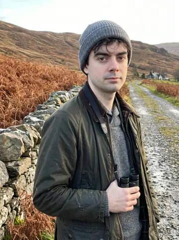 Cathal, AI character: a farm track above the estate lodge at the head of a Highland glen, leaning on an old dry-stone wall,…