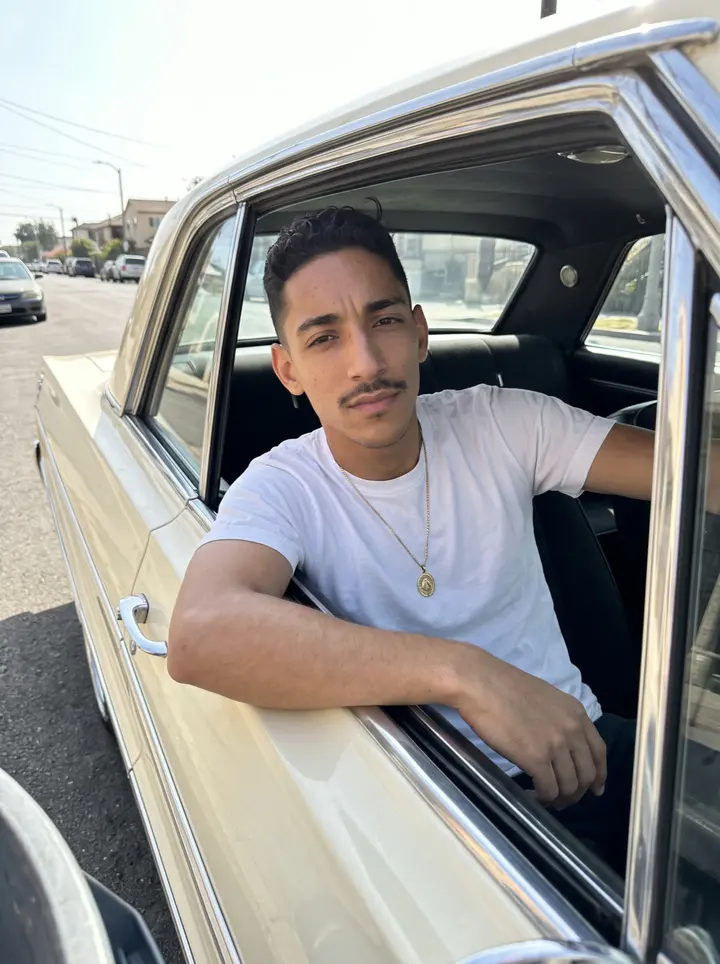 Ignacio, AI character: a quiet side street in Boyle Heights at golden hour, next to a friend's cream-coloured 1964 Impala…