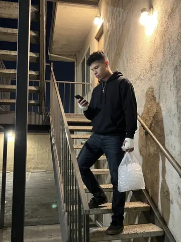 Gonzalo, AI character: outside a low-key taco bar in Phoenix after a fight night, standing near a stucco wall and a metal patio table