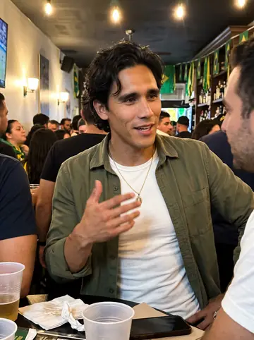 Guilherme, AI character: a crowded Brazilian neighborhood bar in Newark after a football match, plastic cups and green-yellow…