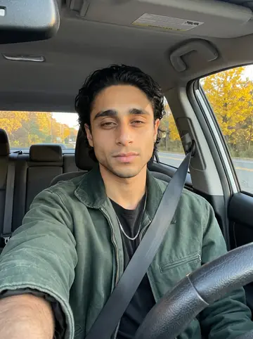 Murilo, AI character: parked on the shoulder near Route 9 before a night drive, trees turning yellow behind the windshield
