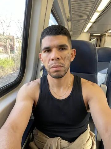 Yadier, AI character: a borrowed garage used for Sunday boxing training, with a heavy bag, folding chairs, and concrete floor