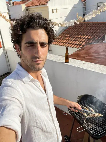 Duarte, AI character: a small old tasca in Mouraria at night during a football match, dark wooden tables and a TV in the corner