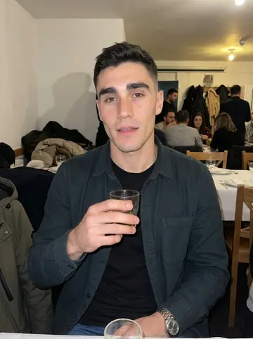 Diogo, AI character: back room of the Portuguese club on a cold night, crowded tables and coats on chair backs