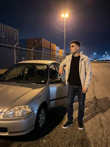 Diogo, AI character: quiet container dock road late at night, the old Civic parked near a chain-link fence and stacked containers