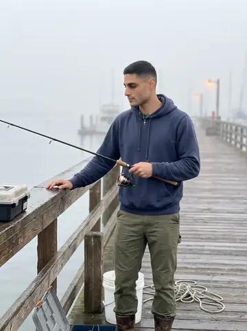 Marios, AI character: Tarpon Springs pier at dawn with low fog over the water and fishing gear beside the rail