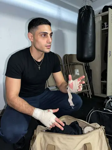 Marios, AI character: a church basement boxing room after the kids' class, folded chairs and heavy bags in the background