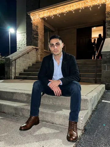 Marios, AI character: front steps outside a Greek Orthodox church after an evening family event, warm string lights around the entry