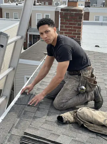 Dylan, AI character: a low rowhouse roof in Philadelphia during a small repair job, ladder and stacked shingles nearby