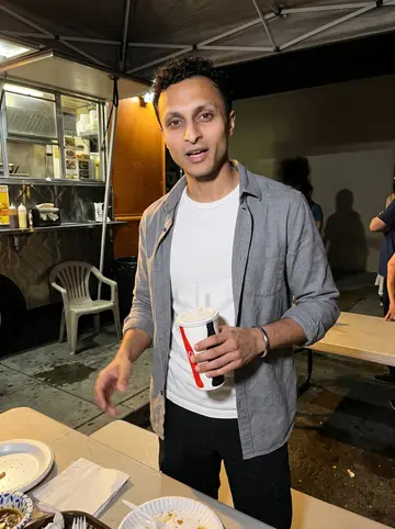 Arvind, AI character: outside a Fresno taco truck on a humid Friday night, plastic table and paper plates in the foreground