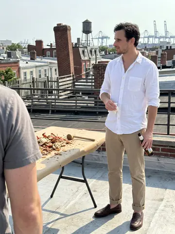 Dexter, AI character: a crowded Baltimore crab house, picnic table covered in brown paper, steamed crabs and a mallet in front…