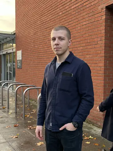 Keir, AI character: outside the Lewisham civic offices after a council software demo, brick wall and bike racks behind him