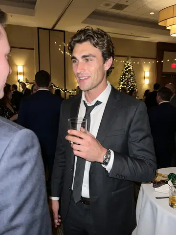 Vance, AI character: the firm's holiday party in a hotel ballroom in Denver, string lights and a Christmas tree behind him,…