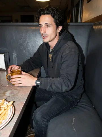 Demetrius, AI character: late-night Gulfport diner booth after work, coffee mug and a plate of fries on the table