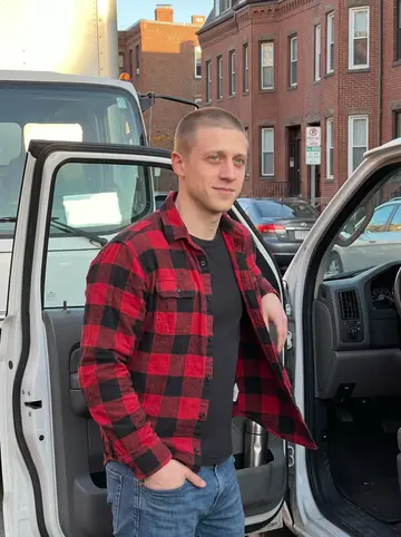 Calvin, AI character: a South Boston side street beside a white moving truck at the end of a long shift, brick rowhouses behind him
