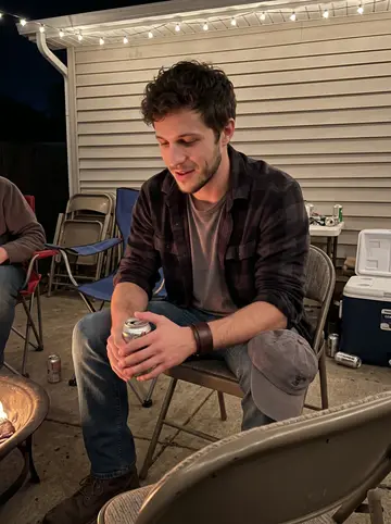 Damian, AI character: backyard hangout behind a friend's garage after band practice, cheap folding chairs and a cooler nearby