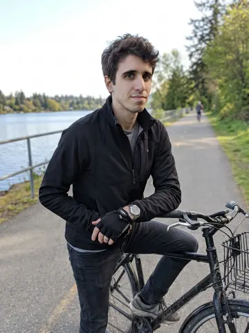 Curtis, AI character: the Burke-Gilman trail near the water in Seattle, stopped beside his black commuter bike after an early ride