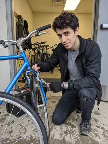 Curtis, AI character: a covered community-center doorway on a rainy Sunday morning, kids' bikes lined up for repairs