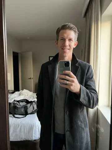 Hudson, AI character: outside his boxing and conditioning gym in Houston, standing in the open roll-up doorway after the last class