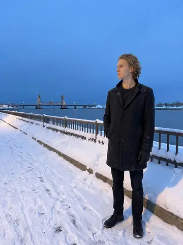 Leevi, AI character: Canal Park after a lake-effect squall, snow piled along the railings and the lift bridge lights small in…