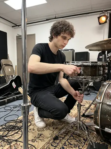 Finbar, AI character: a small rehearsal room behind a theatre, his battered 1974 Ludwig drum kit set up on a worn rug
