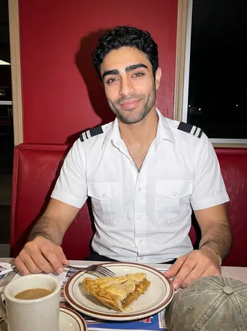 Tariq, AI character: a 24-hour diner outside Amarillo, vinyl booth, coffee cup and slice of pie on the table after a late arrival