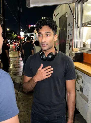 Tejas, AI character: outside a taco truck after closing time near East Sixth, friends cropped at the edges of the frame