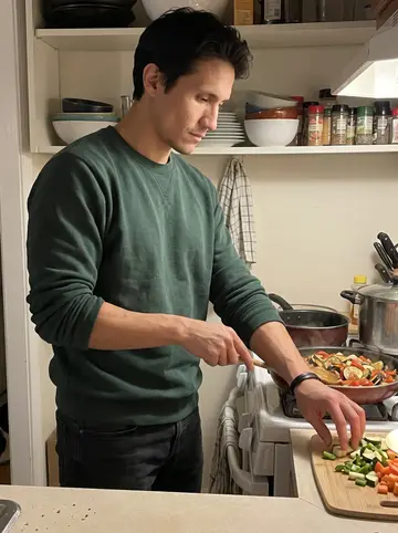 Erwan, AI character: his tiny Dorchester kitchen with a crowded stove and a pan of ratatouille too full for the burner