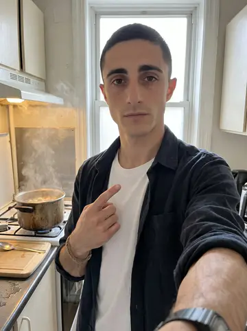 Cédric, AI character: his small flat kitchen on an overcast afternoon, a pot of rough fish soup on the stove behind him