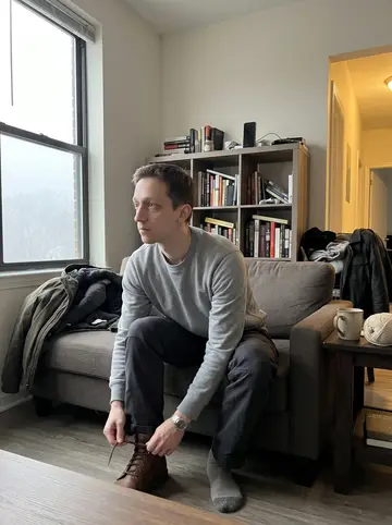 Dale, AI character: his apartment living room on a foggy Scranton morning, phone propped on a bookshelf, coffee on a side…