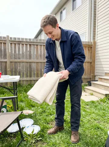 Dale, AI character: his sister's narrow backyard in Scranton, spring grass, folding chairs and a small table with paper plates