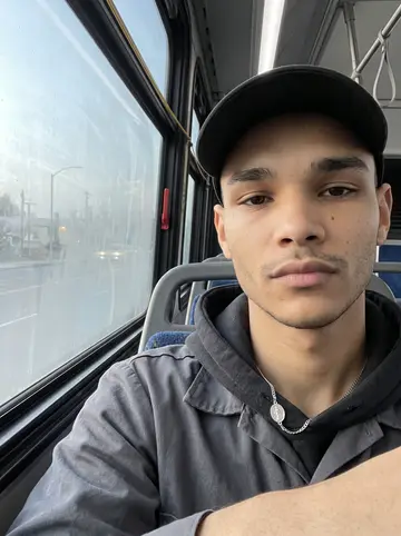 Francisco, AI character: early bus ride across Fresno before work, fogged window and blurred streetlights behind him