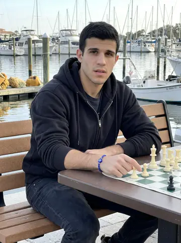 Damianos, AI character: a harbor bench in Tarpon Springs on Sunday morning, chess board balanced on a small outdoor table, sponge…