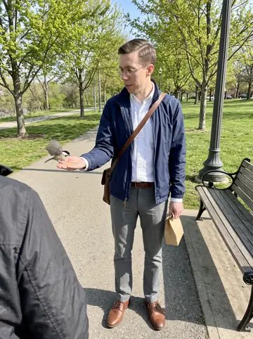 Boyd, AI character: a downtown Dayton sidewalk near the Montgomery County Courthouse, stone steps and columns behind him, a…