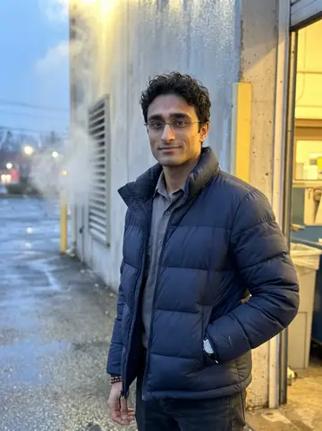 Hakan, AI character: outside the industrial laundry plant in Paterson just after his night shift, steam coming from a side vent…