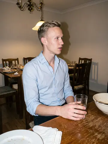 Bas, AI character: his family's dining room during a Sunday lunch that ran into evening, polished wood table and old chairs…