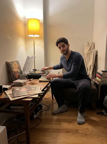 Amílcar, AI character: his small apartment living room late at night, fado records beside a scratchy turntable and chair parts…