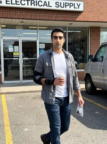 Nabil, AI character: outside an electrical supply store in Dearborn on a bright morning while he is on medical leave, parking…