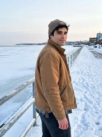 Bailey, AI character: Duluth lakefront near Canal Park with ice on Lake Superior behind him, late afternoon after a service call