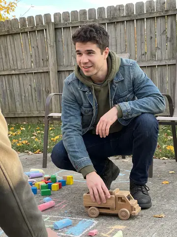 Corey, AI character: his sister's small backyard in the Cincinnati suburbs during a family afternoon, sidewalk chalk and toy…