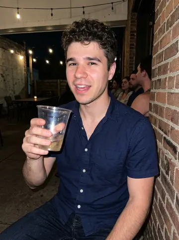 Corey, AI character: a casual Cincinnati neighborhood bar patio after a friend's birthday, string lights and brick wall behind him
